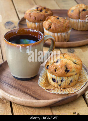 Muffin ai mirtilli e la tazza di caffè sul piatto di legno Foto Stock