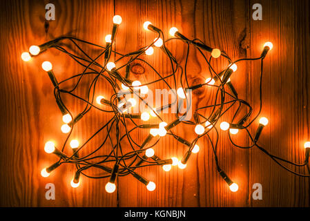 Incandescente albero di natale luci giacente su di un pavimento in legno Foto Stock