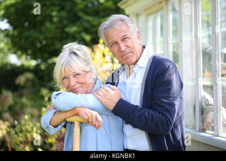 Coppia senior in piedi da serra in giardino Foto Stock