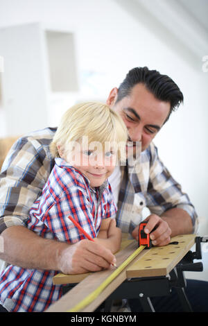 Padre con kid misurazione asse di legno Foto Stock