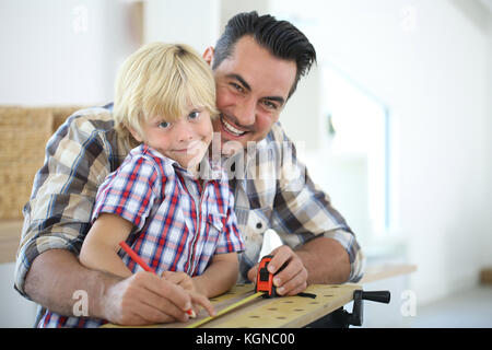 Padre con kid misurazione asse di legno Foto Stock