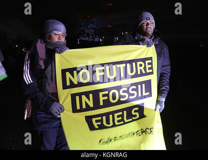 Grevenbroich, Germania. 10 novembre 2017. I rappresentanti delle isole Figi tengono un poster con lo slogan "No Future in Fossil Fuels" di fronte alla centrale a carbone lignite di Neurath del fornitore di energia RWE di Grevenbroich, Germania, 10 novembre 2017. L'organizzazione ambientalista sta conducendo una campagna con immagini proiettate sulla torre di raffreddamento della centrale elettrica per un maggiore impegno nei confronti del cambiamento climatico durante la Conferenza mondiale sul clima di Bonn, in Germania. Credito: dpa Picture Alliance/Alamy Live News Foto Stock