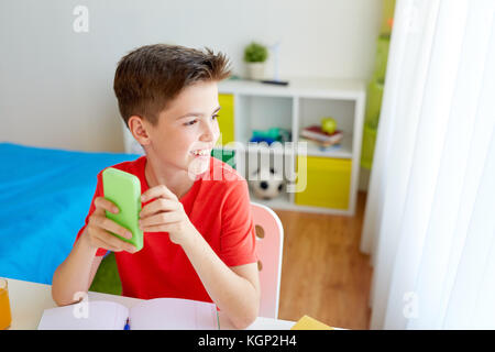 Studente ragazzo con lo smartphone a distrarre dallo studio Foto Stock