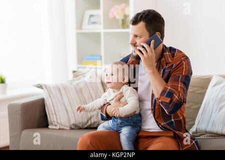 Padre con il bambino chiamando sullo smartphone a casa Foto Stock