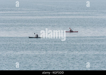 Due pescatori di mare canoa kayak da mare stagliano contro l'acqua. Linea per la pesca dello sgombro nelle acque poco profonde vicino a Par, Cornwall. Il concetto di isolamento. Foto Stock