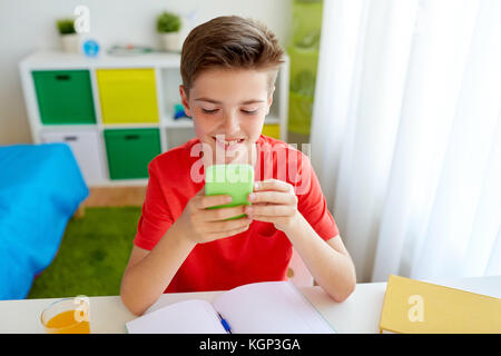 Studente ragazzo con lo smartphone a distrarre dallo studio Foto Stock