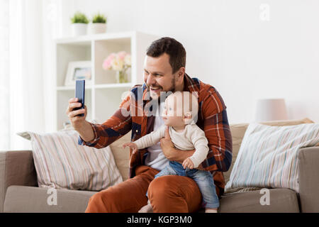 Padre Felice con baby boy tenendo selfie a casa Foto Stock