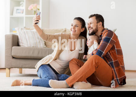 Il padre e la madre con bambino tenendo selfie a casa Foto Stock