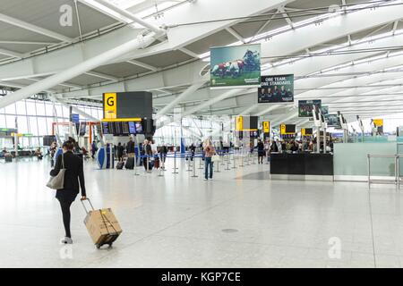 Una passeggero donna arriva per il check-in nella sala partenze del Terminal 5 dell'aeroporto di Heathrow Foto Stock