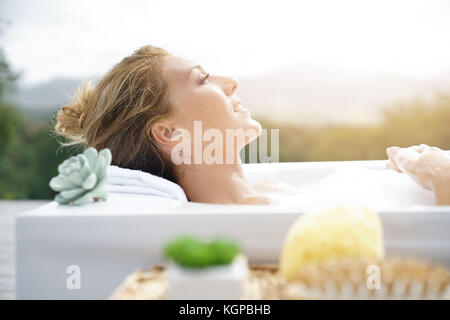 Vista di profilo di donna relax nella vasca da bagno esterna Foto Stock