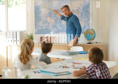 Insegnante in piedi in aula, i ragazzi che frequentano lezione di geografia Foto Stock