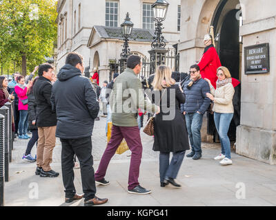 Turisti e sightweers coda per posare con una sentinella montato della regina della vita delle guardie al di fuori dell'Horse Guards building a Whitehall a Londra, Inghilterra Foto Stock