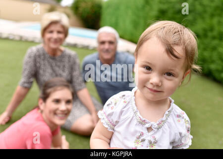 Ritratto di carino 2-year-old girl, famiglia in background Foto Stock