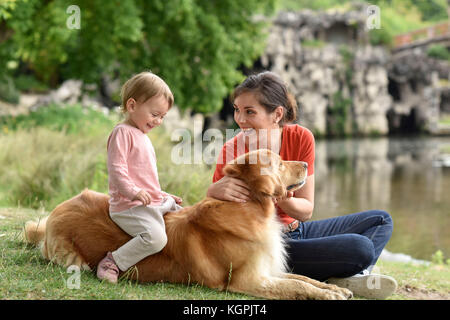 Donna e bambina gioca con il golden retriever cane Foto Stock
