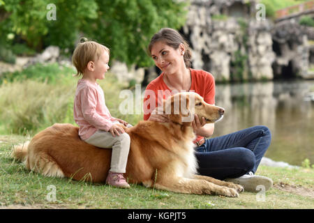 Donna e bambina gioca con il golden retriever cane Foto Stock