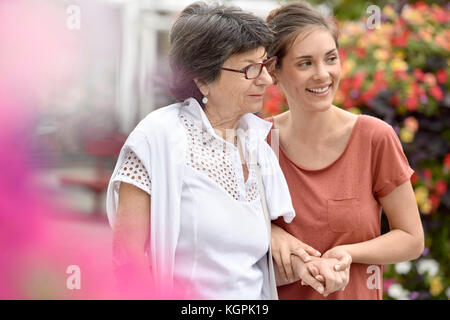 Home caregiver aiutando donna disabile a piedi con stampella Foto Stock