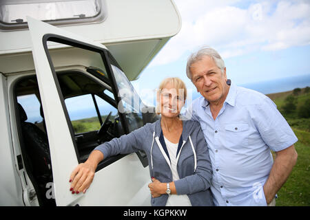 Felice coppia senior in piedi di fronte a camping car Foto Stock