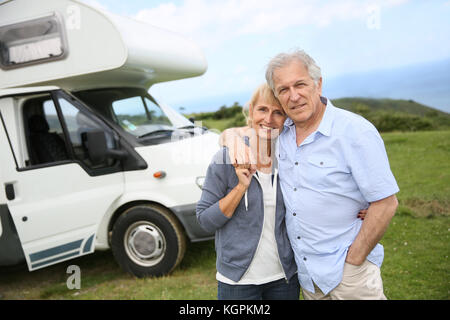 Felice coppia senior in piedi di fronte a camping car Foto Stock