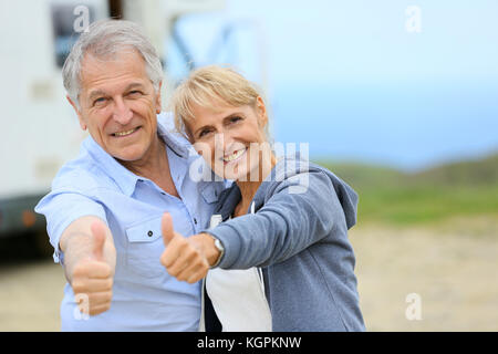 Allegro coppia senior in piedi da camper sulla strada stop Foto Stock