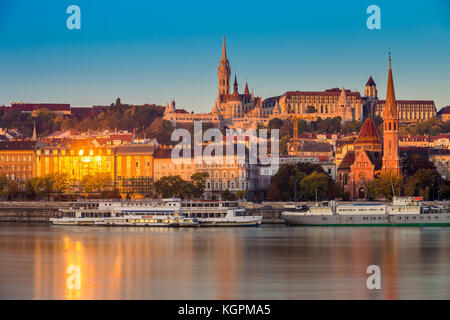Budapest, Ungheria - ora d'oro al mattino a Buda con il Castello di Buda, la chiesa di San Mattia e il Bastione dei pescatori con vecchie navi su Ri Foto Stock