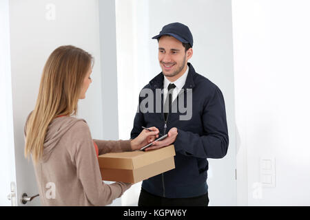 Donna firma ricevuta della consegna del pacchetto Foto Stock