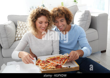 Allegro giovane a casa avendo la pizza per cena Foto Stock