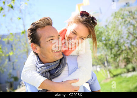 L uomo dando piggyback ride per donna in posizione di parcheggio Foto Stock