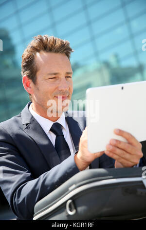 Imprenditore seduto fuori ufficio e utilizzando tablet Foto Stock