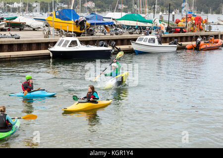 Giovani kayakers formazione in Falmouth Harbour, UK con quayside e barche in background. istruttore dimostrando eskimo roll Foto Stock