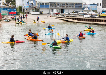 Giovani kayakers formazione in Falmouth Harbour, UK con quayside e barche in background. Foto Stock