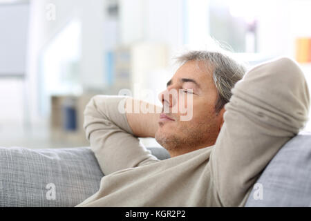 L'uomo prendendo un pisolino in divano a thome Foto Stock