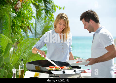 Allegro giovane la preparazione di cibi cotti alla griglia su barbecue Foto Stock