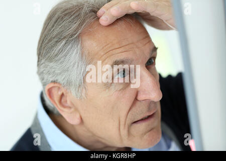 Senior uomo guardando la perdita dei capelli in specchio Foto Stock