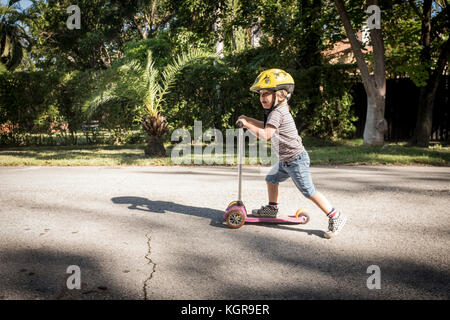 Un giovane di 3 anno vecchio ragazzo gioca sul suo scooter Foto Stock