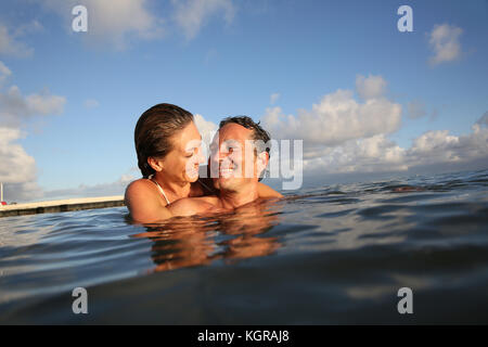 Paio di nuoto in mare al tramonto Foto Stock