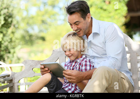 Papà e figlio giocando con la compressa al di fuori Foto Stock