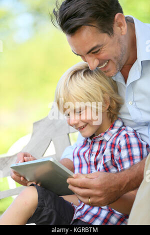 Papà e figlio giocando con la compressa al di fuori Foto Stock