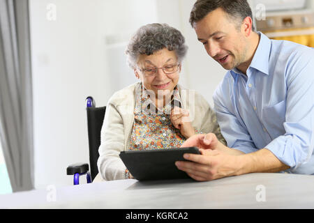 L'uomo con la donna anziana con tavoletta digitale Foto Stock
