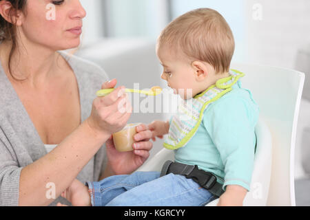 Madre dando salsa di frutta per baby boy Foto Stock