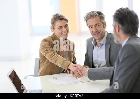 Matura in ufficio bancario agitando la mano per consulente finanziario Foto Stock
