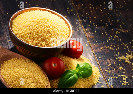 Ciotola di couscous crudo su un tavolo di legno. Foto Stock