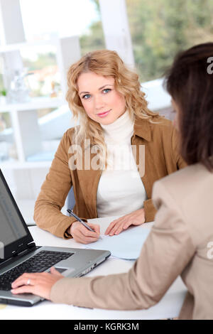 Bella donna firma contratto in compagnia di assicurazioni Foto Stock