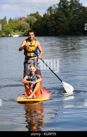 Matura in sella stand-up-pala sul fiume Foto Stock