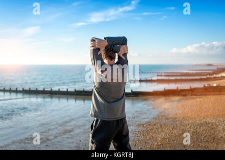 L uomo lo stiramento dal mare, in fase di riscaldamento prima di allenamento. Foto Stock