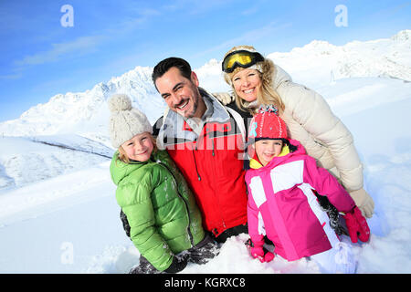 Allegro famiglia avente una buona volta in montagna innevata Foto Stock