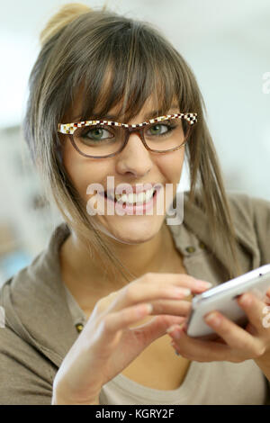 Giovane donna con occhiali websurfing sullo smartphone Foto Stock