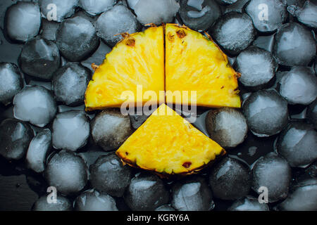 Su uno sfondo nero con ananas fresco frutta di ghiaccio Foto Stock