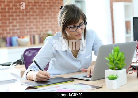 Creative giovane donna che lavorano in ufficio con tavoletta grafica Foto Stock