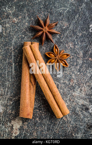 Bastoncini di cannella e anice stella sul vecchio tavolo da cucina. Foto Stock