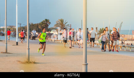 Barcellona, Spagna - 20 Giugno 2017 : uomo correre sulla spiaggia nel mezzo della Walkers dopo la fine di una giornata di lavoro Foto Stock